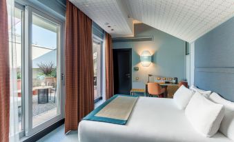 a modern hotel room with a large bed , white bedding , and blue walls , next to a sliding glass door leading to a balcony at Room Mate Giulia