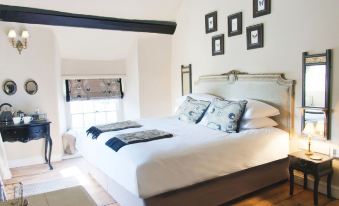 a cozy bedroom with a large bed and several framed pictures on the wall , creating a warm and inviting atmosphere at The White Hart