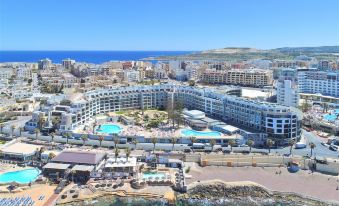 a panoramic view of a city with buildings , pools , and the ocean in the background at DoubleTree by Hilton Malta