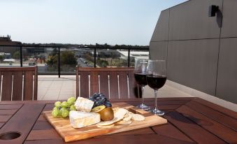 a wooden cutting board with cheese and grapes next to a glass of red wine at The Penthouse