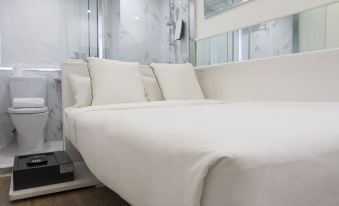 In the middle room, there is a bed with white sheets and pillows, located next to an open doorway at Mini Central