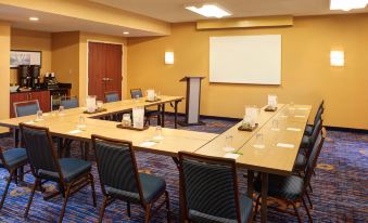a conference room with several tables , chairs , and a projector screen set up for a meeting at Courtyard Detroit Dearborn