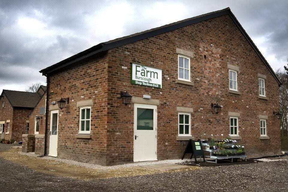 "a brick building with a sign that says "" farm "" and several benches in front of it" at The Farm Burscough
