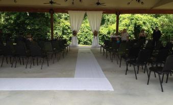 a wedding ceremony taking place under a covered area , with rows of chairs arranged for guests at Bicentennial Inn