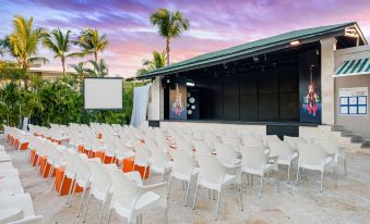 a large outdoor event space with white chairs and an audience , set up for a presentation or performance at Emotions by Hodelpa - Juan Dolio