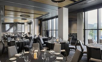 a large dining room with multiple tables and chairs arranged for a formal event , possibly a wedding reception at Vibe Hotel Melbourne Docklands