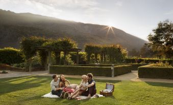 a group of people are enjoying a picnic in a lush green field with mountains in the background at Bernardus Lodge & Spa