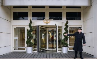 "a man in a black coat stands in front of a large white building with the name "" sofitel "" displayed above" at Sofitel London Gatwick