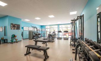 a well - equipped gym with various exercise equipment , such as treadmills , weight machines , and benches , arranged in a spacious room at Quality Hotel San Martino