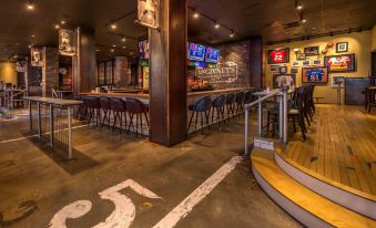 a bar with multiple stools and tables , as well as a large number 5 on the wall at Four Points by Sheraton Juneau