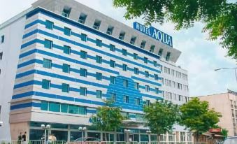 a large hotel building with blue and white stripes , located on a city street with trees in the background at Aqua Hotel