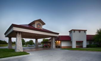 an entrance to a hotel with a large stone archway and a red roof , set against a clear blue sky at Best Western Wichita North