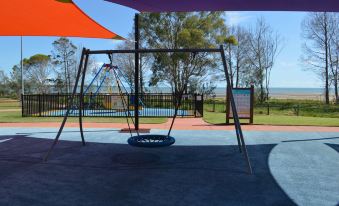 an empty playground with swings and a swing set , under an orange and purple canopy at Best Western Ambassador Motor Lodge