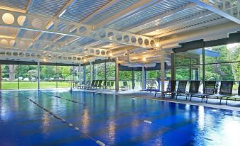a large indoor swimming pool surrounded by glass walls , with several chairs placed around the pool area at Macdonald Berystede Hotel & Spa