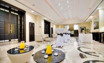 a large , elegant room with white tables and chairs , black and white marble flooring , and yellow candles on pedestals at AX The Palace