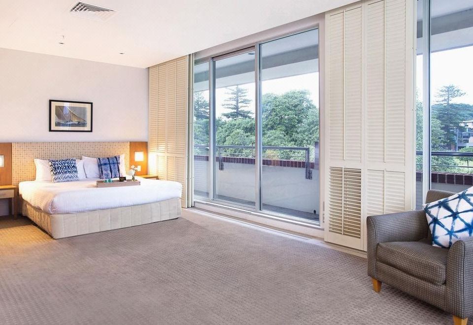 a modern bedroom with large windows , a comfortable bed , and a couch near the window at Watsons Bay Boutique Hotel