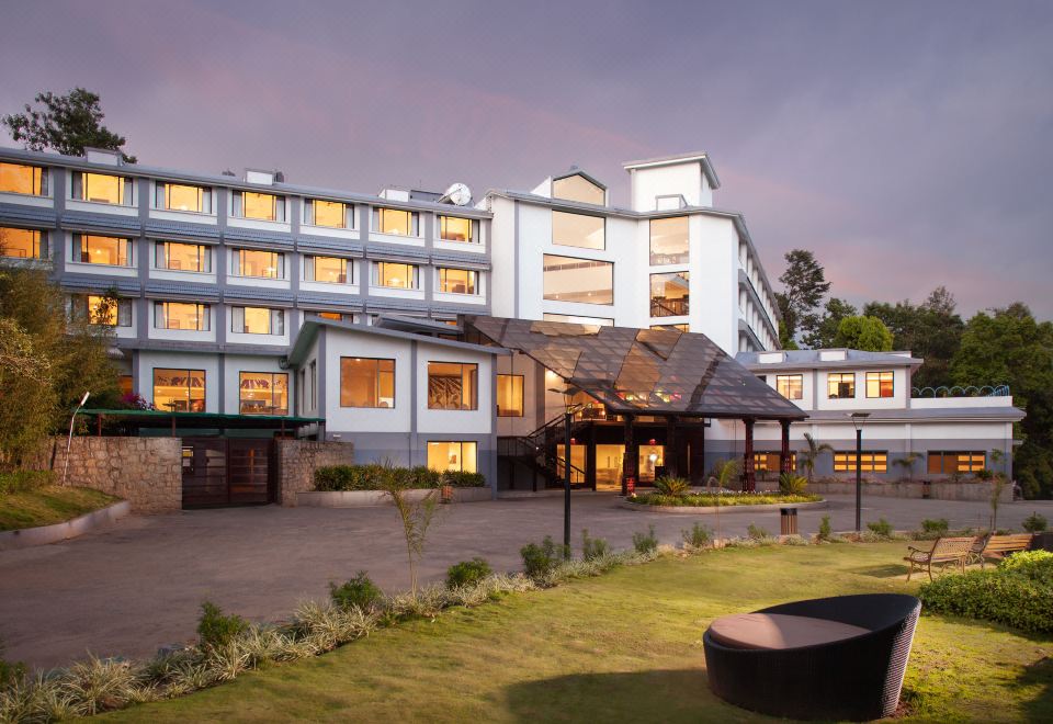 a large hotel building surrounded by grass and trees , with a gate in front of it at Sterling Munnar