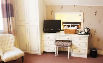 a small bedroom with a bed , a dresser , and a television mounted on the wall at Roseview Alexandra Palace Hotel
