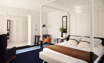 a white bedroom with a large bed , a chair , and a rug on the floor at Hotel Pulitzer Buenos Aires