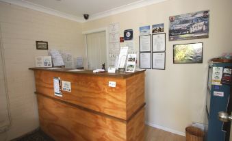 a hotel lobby with a wooden reception desk and various signs on the wall , creating a welcoming atmosphere at Picton Valley Motel Australia