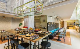 a large dining area with a long wooden table surrounded by chairs , filled with various food items and utensils at Room Mate Giulia