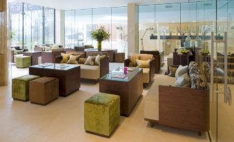 a modern , well - lit lounge area with multiple couches and chairs arranged in a sitting area at Ockenden Manor Hotel & Spa