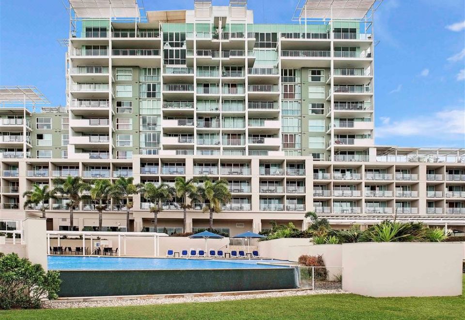 a tall apartment building with many balconies and a pool in front of it at Pelican Waters Resort