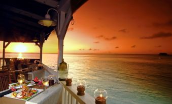 a dining table set up on the deck of a boat , overlooking the ocean at sunset at Grand Case Beach Club