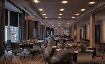 a large , empty banquet hall with multiple round tables and chairs , set for a formal dinner or event at Malmaison Dundee