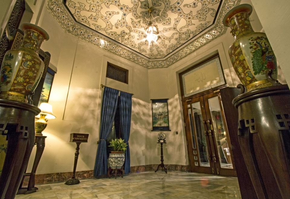 a well - decorated foyer with a chandelier hanging from the ceiling , a vase of flowers on a table , and a potted plant in the at Faisalabad Serena Hotel