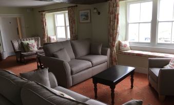 a cozy living room with a couch , chairs , and a coffee table in front of a window at Hartland Quay Hotel