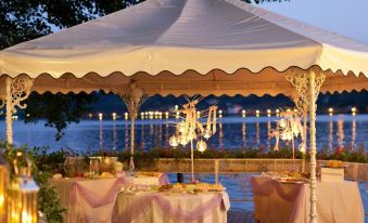 a large white tent set up on a deck overlooking a body of water , creating an outdoor dining experience at Hotel l'Approdo