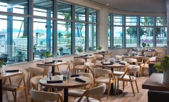 a modern restaurant with wooden tables and chairs , large windows offering views of the outdoors at Treasure Island Beach Resort