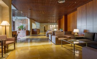 a modern lobby with a wooden ceiling and brown furniture , including couches and a coffee table at Exe Layos Golf