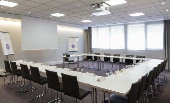 a large conference room with multiple tables and chairs arranged for a meeting or event at Novotel Chateau de Versailles