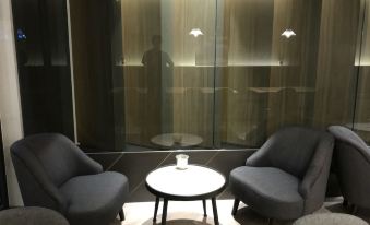 a modern living room with two gray armchairs , a round table , and a wall - mounted light at Hub Hotel