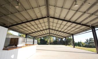 a large , open - air shelter with a metal roof and white walls , providing shelter for workers and vehicles at Ardeena