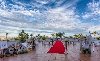 a red carpet leading up to a building , surrounded by chairs and tables , set up for an outdoor event at Playadulce