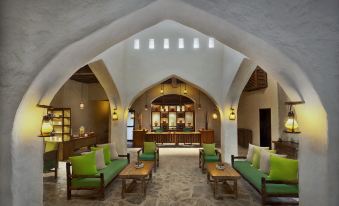 a spacious room with a dining table , chairs , and couches , surrounded by a stone floor at Six Senses Zighy Bay