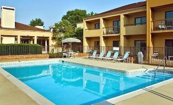 a large swimming pool with lounge chairs and a slide is surrounded by buildings , including an apartment building at Courtyard Richmond West