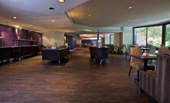 a spacious room with wooden floors , large windows , and various furniture , including chairs and tables at Doubletree by Hilton Montreal