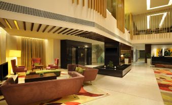 a modern hotel lobby with various seating options , including couches and chairs , as well as a large fountain in the background at Four Points by Sheraton Ahmedabad