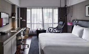 The bedroom is furnished with large windows, a bed, and a desk in the middle at Sofitel Saigon Plaza