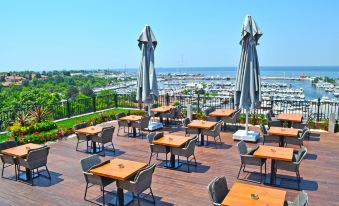 a rooftop dining area with several tables and chairs , providing a pleasant outdoor setting for guests at Wyndham Grand Istanbul Kalamış Marina Hotel