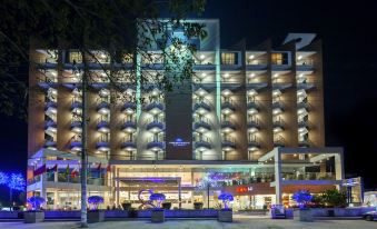 a large hotel with multiple floors and balconies is lit up at night , surrounded by trees at Long Beach Hotel