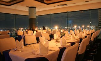 A table is set for dinner in the dining room, offering a view of the city and other locations at Baiyoke Suite Hotel