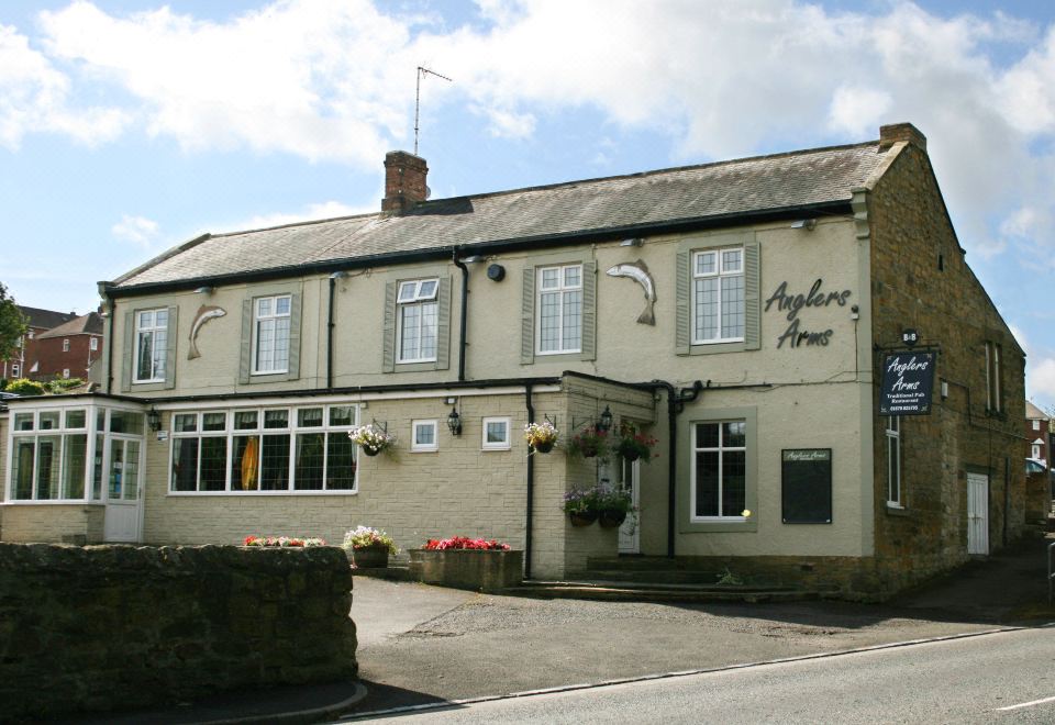 the exterior of the mapleton arms pub , a traditional english pub with white stone exterior and large windows at Anglers Arms