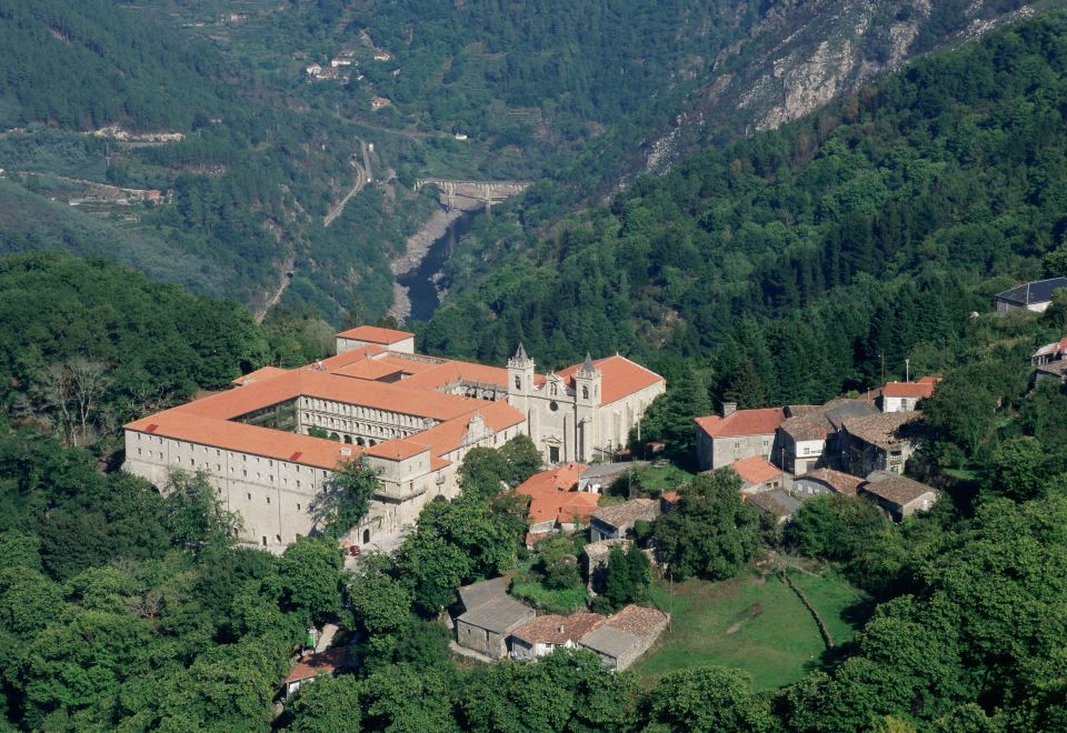 an aerial view of a large building surrounded by trees , with mountains in the background at Parador de Santo Estevo