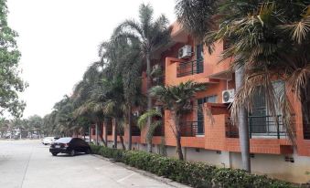 a row of apartment buildings with palm trees lining the street and a car parked in front at Rawanda Resort Hotel