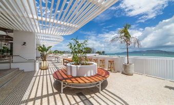 a rooftop patio with a dining table , chairs , and potted plants overlooking the ocean and beach at The Ville Resort - Casino